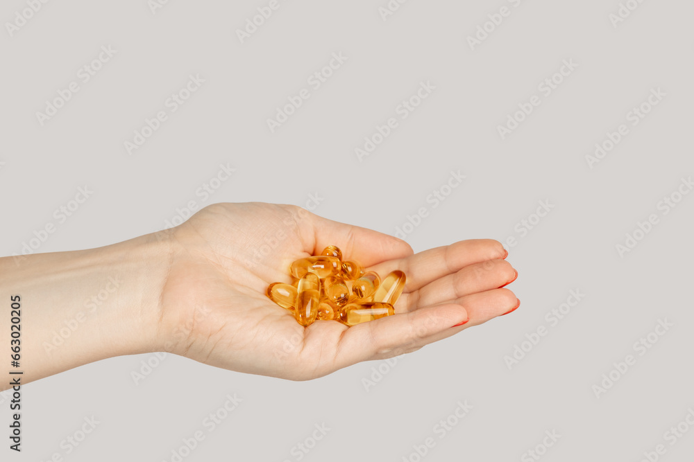 Closeup of woman hand handful of pills capsules, nutritional supplement, vitamins, medicine. Indoor studio shot isolated on gray background. Closeup of woman hand handful of pills capsules, nutritional supplement, vitamins, medicine. Indoor studio shot isolated on gray background.