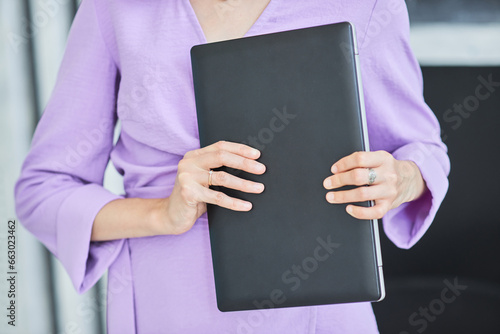 A girl is holding a laptop in her hands - an excellent device for a businesswoman. Technology not only helps speed up learning but also allows you to be mobile.