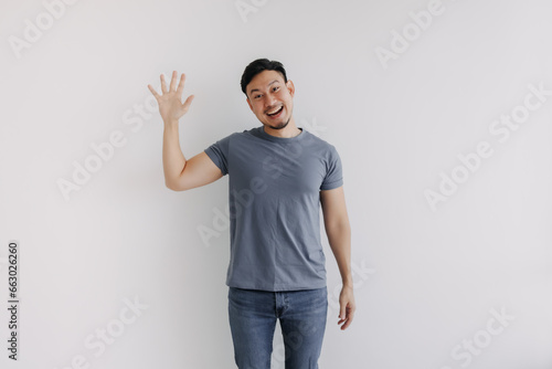 Happy asian man pop out for greeting and say hi, stand isolated on white.