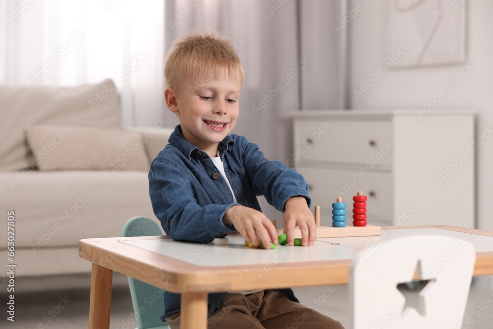 Fototapeta premium Cute little boy playing with stacking and counting game at table indoors. Child's toy