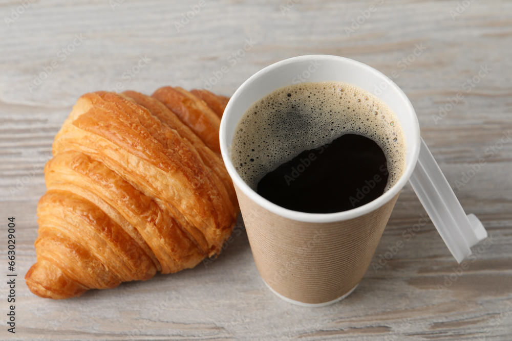 Coffee to go. Paper cup with tasty drink and croissant on white wooden table, closeup Coffee to go. Paper cup with tasty drink and croissant on white wooden table, closeup