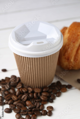 Coffee to go. Paper cup with tasty drink and beans on white table