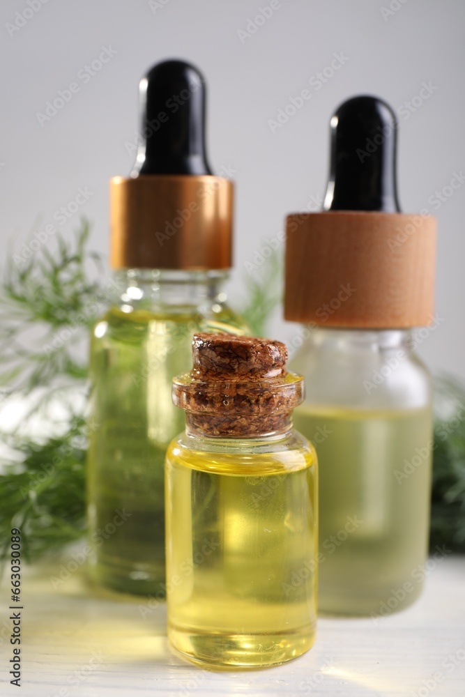 Bottles of essential oil and fresh dill on light table, closeup Bottles of essential oil and fresh dill on light table, closeup