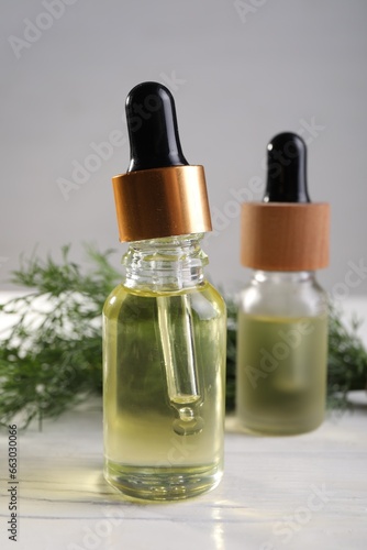 Fototapeta Naklejka Na Ścianę i Meble -  Bottles of essential oil and fresh dill on white table, closeup