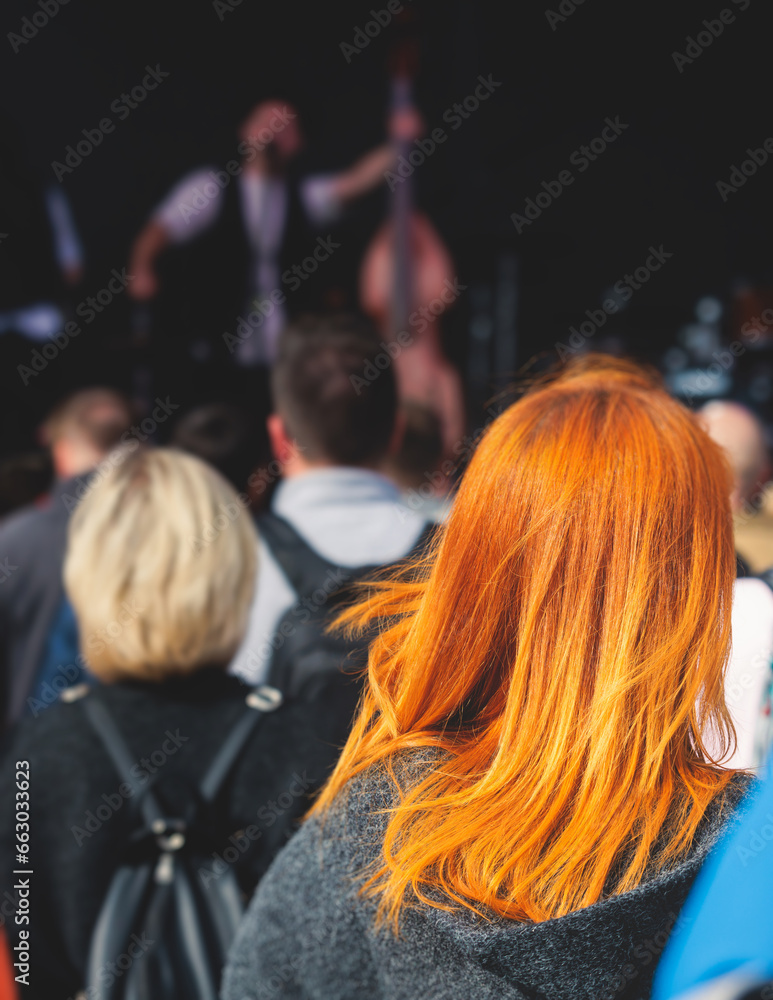 Crowded open air festival concert with scene lights with musicians band on stage at the venue, rock show performance, with concert-goers attendees, audience on dance floor during summer festival Crowded open air festival concert with scene lights with musicians band on stage at the venue, rock show performance, with concert-goers attendees, audience on dance floor during summer festival