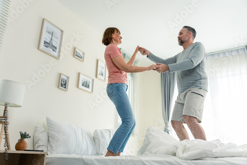 Caucasian senior couple dancing with music together in bedroom at home. 