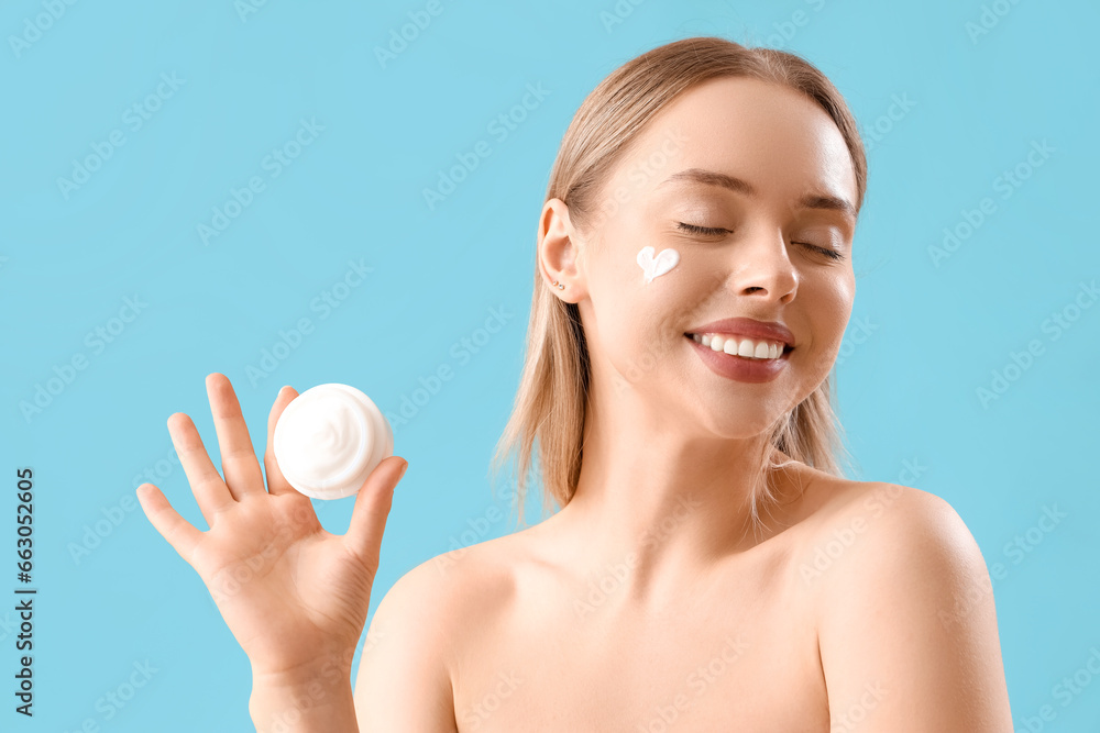 Pretty young woman with facial cream on blue background Pretty young woman with facial cream on blue background