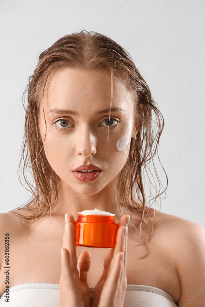 Pretty young woman with facial cream on light background Pretty young woman with facial cream on light background