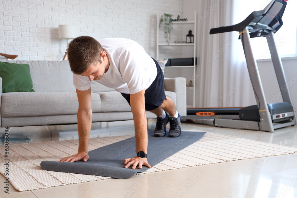 Fototapeta premium Sporty young man doing push-ups at home