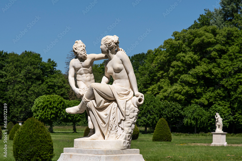 Obraz premium Statue of a couple, a woman and the devil, in a park with lots of vegetation in the Chaalis estate in France