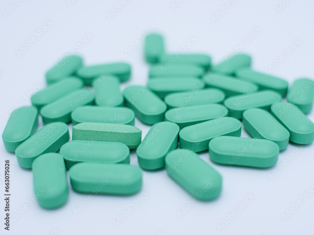 green medical pills and tablets scattered isolated on white background
