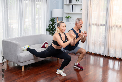 Active and fit senior couple warmup and stretching using furniture before home exercising routine at living room. Healthy fitness lifestyle concept after retirement for pensioner. Clout