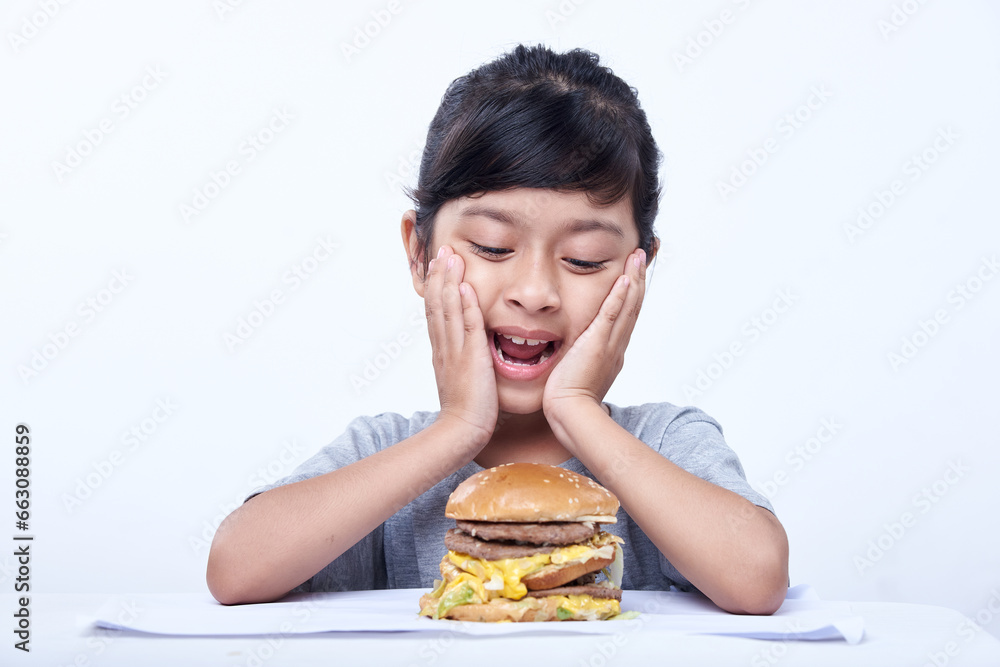 Smiling Little girl with a big cheeseburger with tomato, lettuce, arugula, beef and sauce Smiling Little girl with a big cheeseburger with tomato, lettuce, arugula, beef and sauce