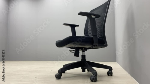 Black office chair sliding on floor indoor room with empty space.