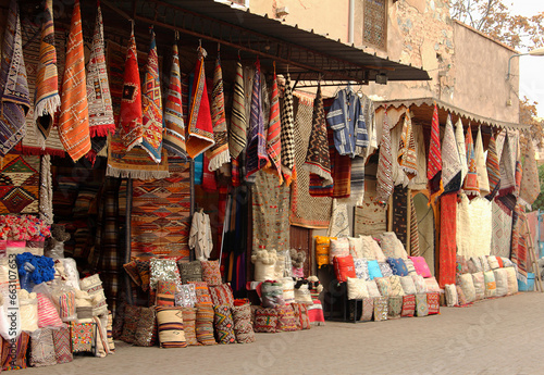 Traditional textile shop with colorful carpets and cushions displayed on the street in Marrakech, Morocco.