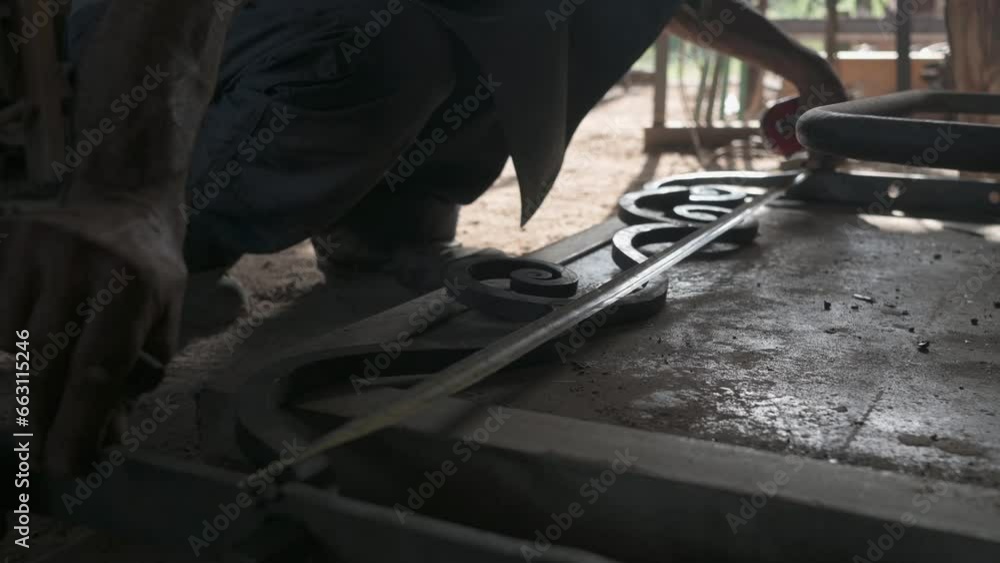 Close-up of a blacksmith's hands measuring a decorative grille in his workshop. Close-up of a blacksmith's hands measuring a decorative grille in his workshop.