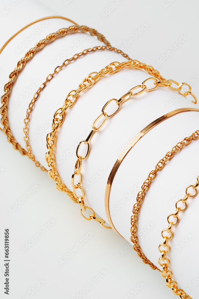 Set of golden bracelets on display on white background - obrazy, fototapety, plakaty 