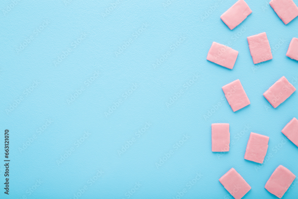Pink sweet chewing gum pads on light blue table background. Pastel color. Closeup. Empty place for text. Top down view. Pink sweet chewing gum pads on light blue table background. Pastel color. Closeup. Empty place for text. Top down view.