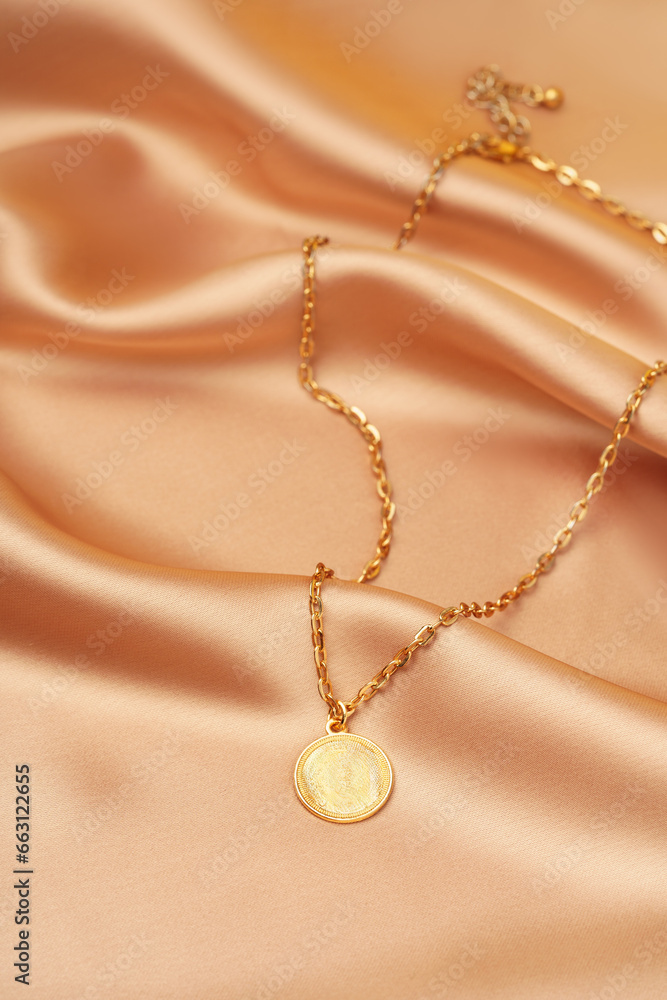 Golden necklace with pendant on silk background Golden necklace with pendant on silk background