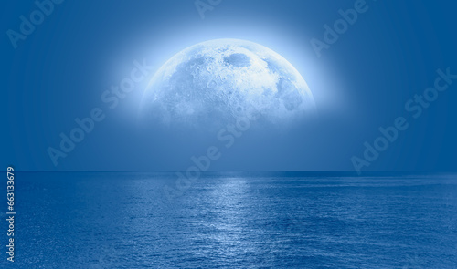 Night sky with blue moon in the clouds over the calm blue sea, many sytars in the background "Elements of this image furnished by NASA