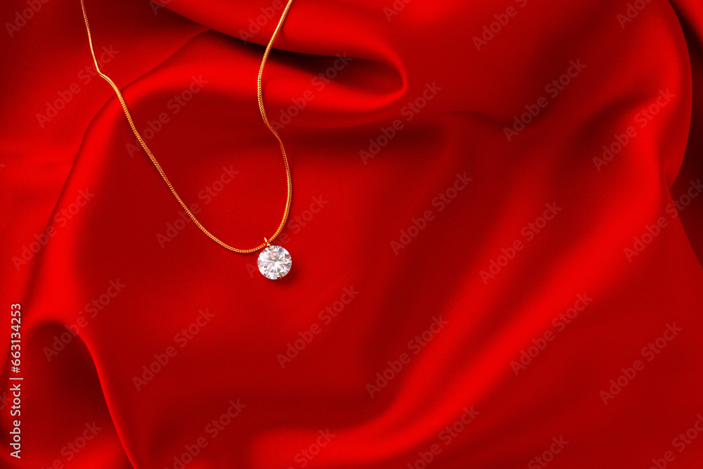 Golden necklace with pendant on red silk background - obrazy, fototapety, plakaty 