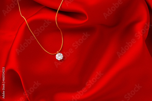 Golden necklace with pendant on red silk background
