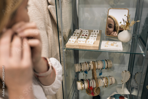 woman wearing earrings in a store in front of the mirror
