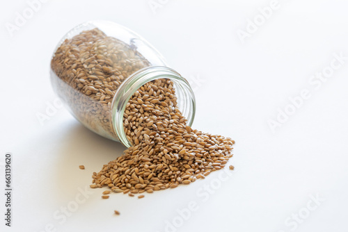 Spelt grains neatly stored in a glass jar against a clean white background, illustrating food storage