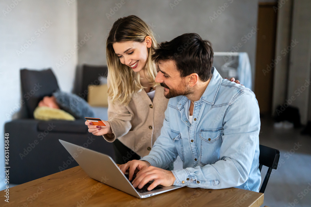 Happy couple at home paying bills or online shopping with laptop and credit card Happy couple at home paying bills or online shopping with laptop and credit card