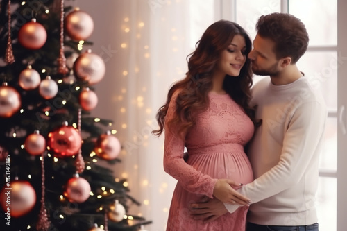A pregnant woman is hugged by a man near the Christmas tree