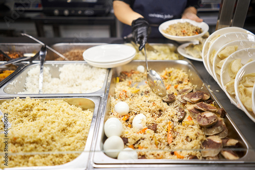 A traditional Uzbek dish called pilaf. Rice with meat, carrots, onions, quail eggs and kazy . Glass Showcase in a buffet or self-service restaurant. photo