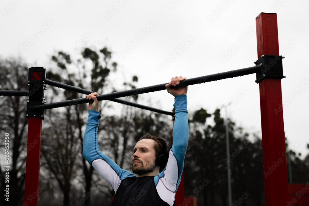 Concept of strength sportsman doing pull up on the horizontal bar outdoors. Young man sports hobby. Power for morning trainings. Motivation to workout every day. Male has healthy lifestyle at wet Concept of strength sportsman doing pull up on the horizontal bar outdoors. Young man sports hobby. Power for morning trainings. Motivation to workout every day. Male has healthy lifestyle at wet