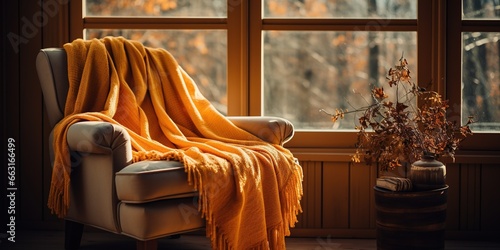 A chair with a blanket on it next to a window. © Coosh448