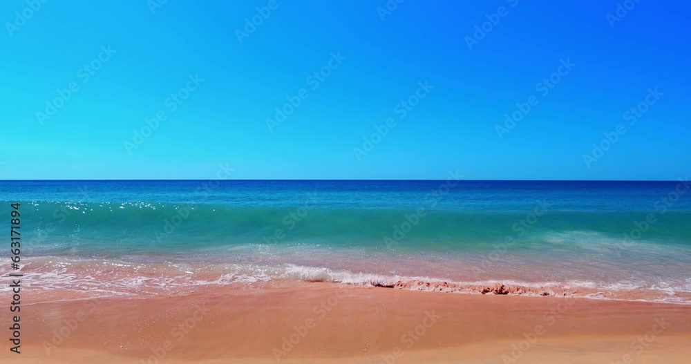 Slow motion wave breaks on perfect sandy beach. Blue sky over ocean horizon Slow motion wave breaks on perfect sandy beach. Blue sky over ocean horizon