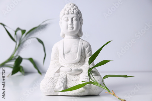 Buddha statue and leaves on white background