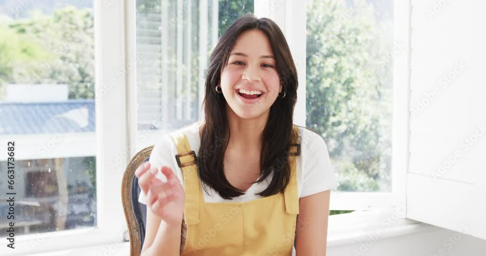 Happy biracial woman having video call waving and smiling in sunny room, copy space, slow motion Happy biracial woman having video call waving and smiling in sunny room, copy space, slow motion