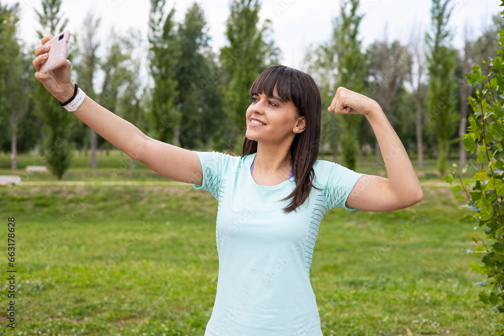Smiling sport woman fitness training outdoors taking a selfie with smartphone. Strong young runner athlete workout. Smiling sport woman fitness training outdoors taking a selfie with smartphone. Strong young runner athlete workout.