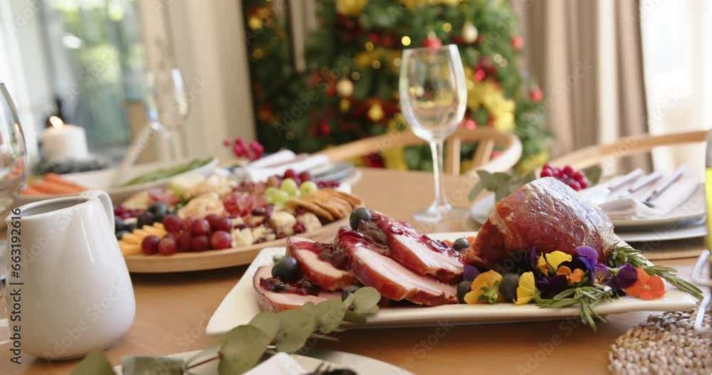 Food on dining table set for christmas celebration meal with tree in background, slow motion Food on dining table set for christmas celebration meal with tree in background, slow motion