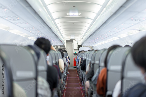 A compact aisle and snug seating within the budget airline cabin, entirely occupied by passengers of Asian descent, prepared for departure. photo