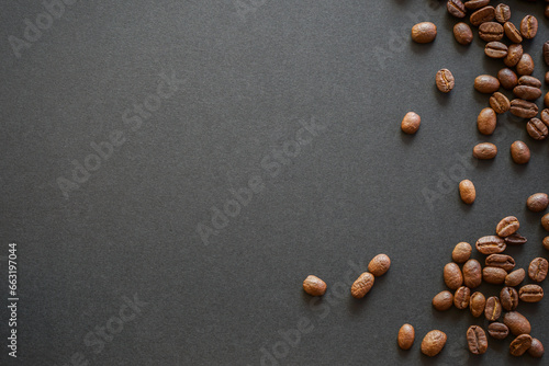 close up of roasted coffee beans on black paper background with copy space for text.