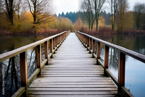 a wooden bridge path over a tranquil lake © altitudevisual