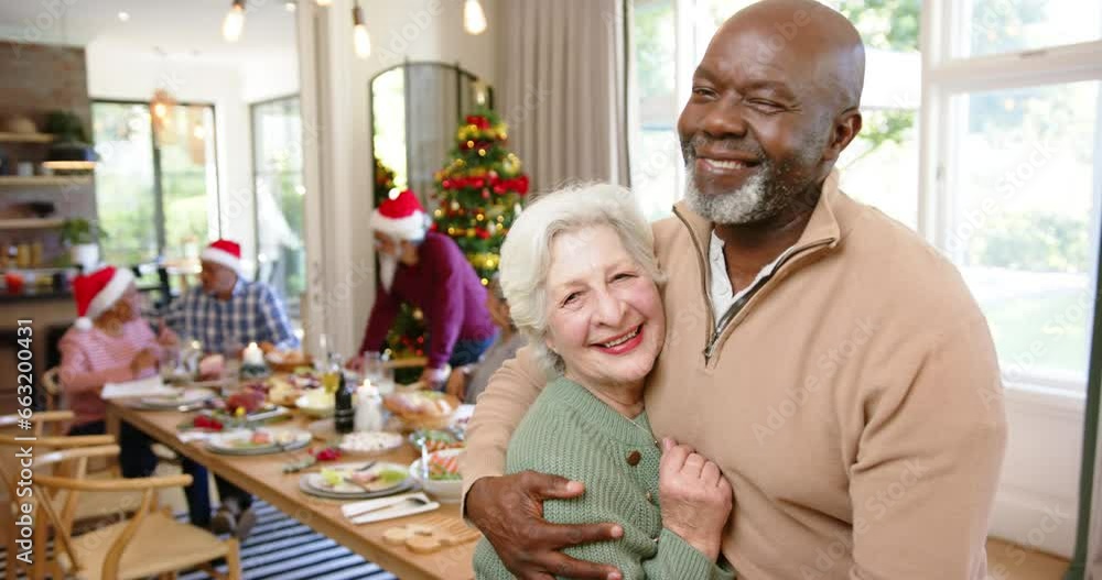 Happy diverse senior couple embracing after christmas meal with friends, copy space, slow motion Happy diverse senior couple embracing after christmas meal with friends, copy space, slow motion