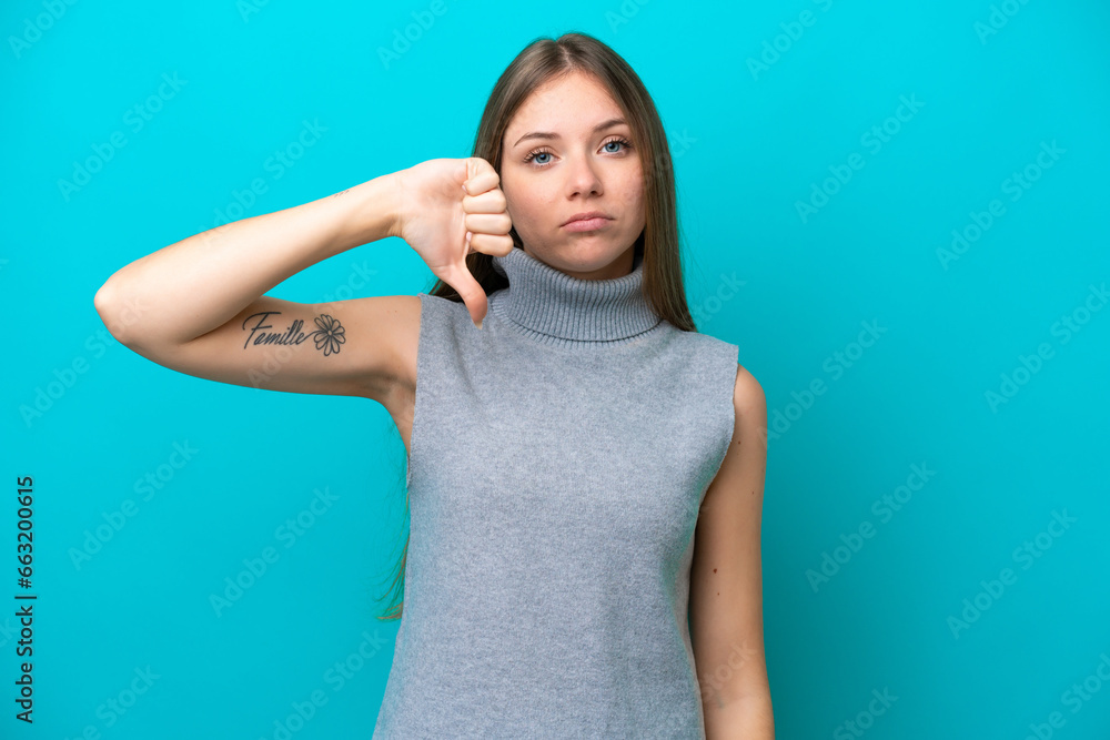 Young Lithuanian woman isolated on blue background showing thumb down with negative expression Young Lithuanian woman isolated on blue background showing thumb down with negative expression