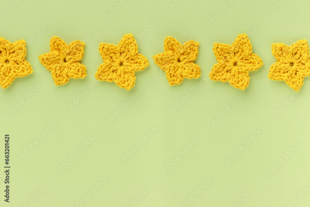 Yellow crocheted flowers row pattern on a green background. Yellow crocheted flowers row pattern on a green background.