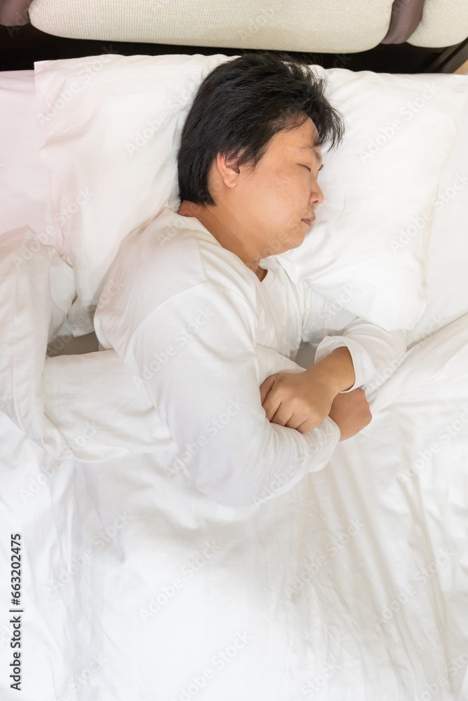 Top view of an exhausted man tosses and turns on a bed all night by restless sleep or insomnia problem. Health issue from anxiety, depression, and stress. Top view of an exhausted man tosses and turns on a bed all night by restless sleep or insomnia problem. Health issue from anxiety, depression, and stress.