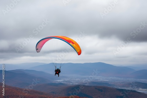 colorful paraglider against a cloudy grey sky