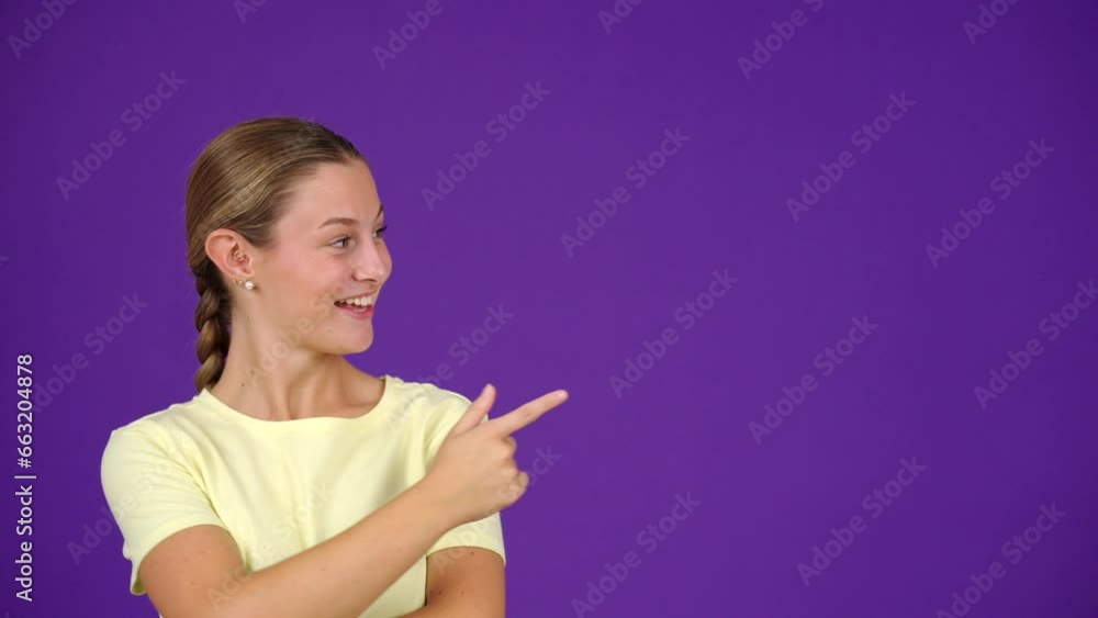 Young surprised woman pointing at copy space isolated on purple background. Young surprised woman pointing at copy space isolated on purple background.