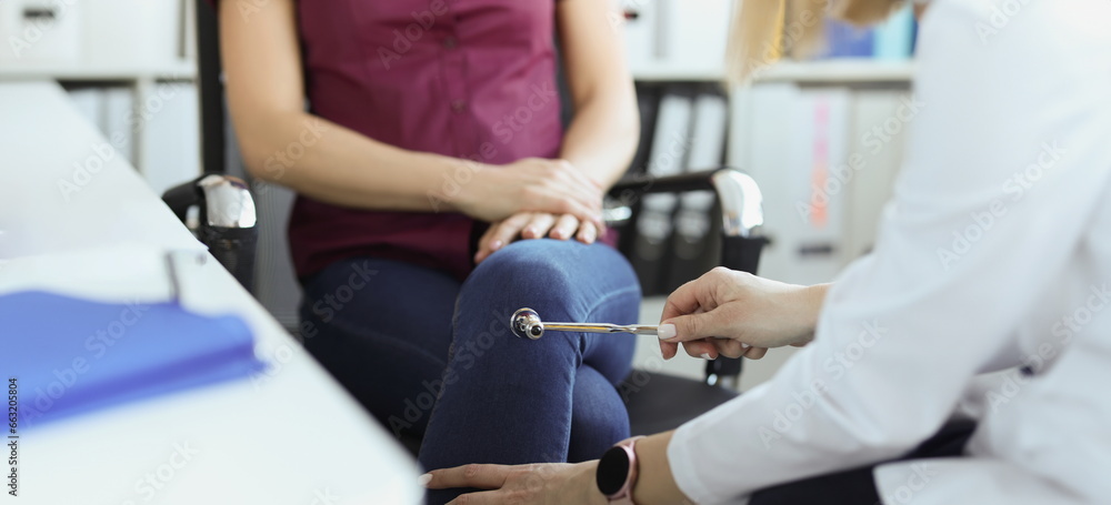 Close-up of doctor neurologist checking knee reflexes of female patient with percussion hammer in clinic. Neurology, checkup, medicine, diagnostics concept Close-up of doctor neurologist checking knee reflexes of female patient with percussion hammer in clinic. Neurology, checkup, medicine, diagnostics concept