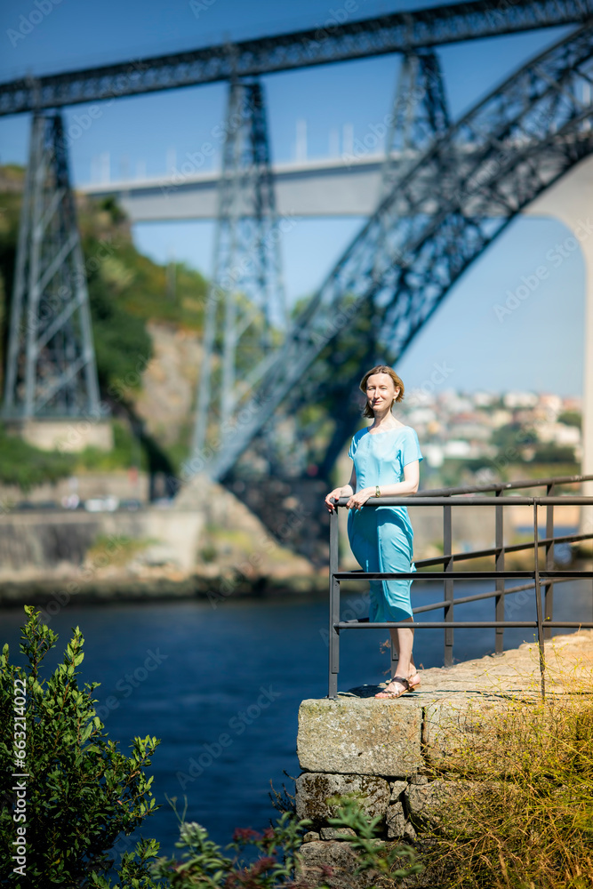 A woman in a blue dress stands on a city promenade. Porto, Portugal.
