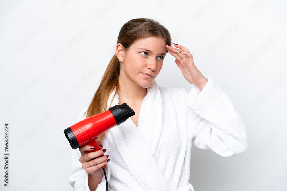 Naklejka premium Young caucasian woman holding hairdryer isolated on white background having doubts and with confuse face expression